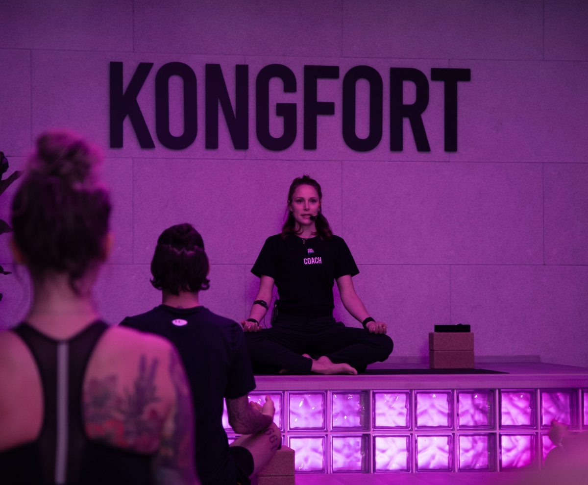Trainerin gibt Anweisungen im Power Yoga Kurs über das Headset im King Kong Club Salzburg.