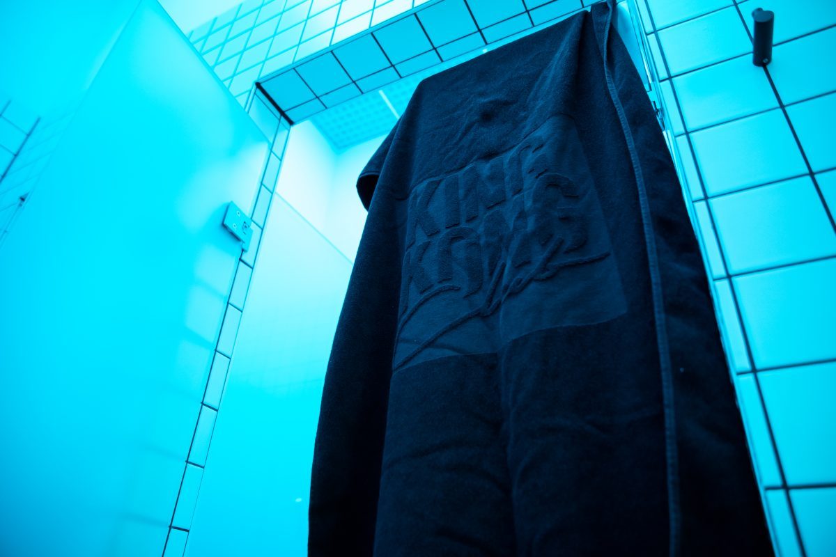 Dunkles Handtuch mit King Kong Club Salzburg Logo hängt an Dusche.